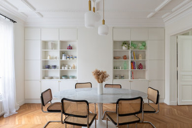 Diseño de comedor actual con paredes blancas, suelo de madera en tonos medios y suelo marrón