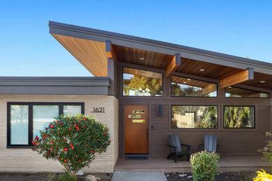 Large 1960s brown house exterior photo in Seattle with a shed roof, a mixed material roof and a brown roof
