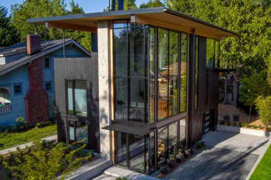 Large contemporary black three-story wood house exterior idea in Seattle with a shed roof