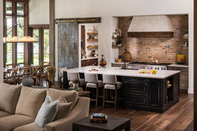 Eat-in kitchen - large traditional l-shaped medium tone wood floor and brown floor eat-in kitchen idea in Orlando with a farmhouse sink, recessed-panel cabinets, black cabinets, brick backsplash, stainless steel appliances, an island and beige countertops