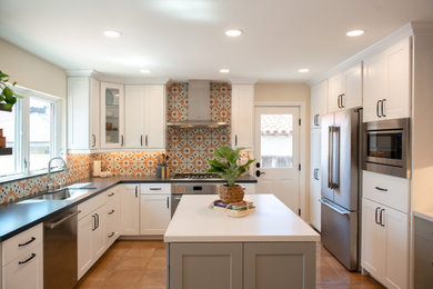 Example of a mid-sized transitional u-shaped enclosed kitchen design in San Diego with an undermount sink, shaker cabinets, white cabinets, soapstone countertops, multicolored backsplash, porcelain backsplash, stainless steel appliances, an island and black countertops