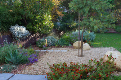 Foto de jardín de secano minimalista grande en primavera en patio trasero con parterre de flores, exposición total al sol, adoquines de hormigón y con metal