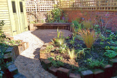 Inspiration for a small bohemian back partial sun garden for summer with a garden path and gravel.