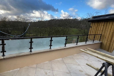 Medium sized modern glass railing balcony in Other with no cover.