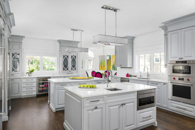 Example of a large transitional u-shaped dark wood floor and brown floor eat-in kitchen design in Chicago with an undermount sink, gray cabinets, quartzite countertops, white backsplash, stainless steel appliances, two islands, white countertops and raised-panel cabinets