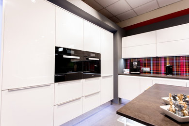 Offene, Große Moderne Küche in L-Form mit integriertem Waschbecken, weißen Schränken, Glasrückwand, schwarzen Elektrogeräten und Kücheninsel in Berlin