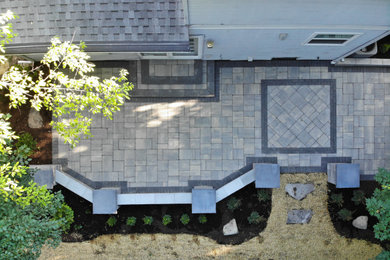 Ejemplo de jardín actual grande en verano en patio trasero con muro de contención, exposición parcial al sol y adoquines de ladrillo