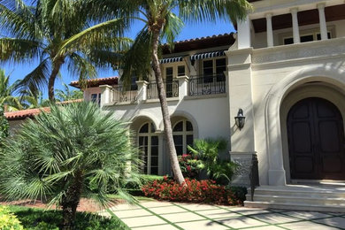 Inspiration for a mid-sized mediterranean two-storey beige house exterior in Miami with stone veneer, a hip roof and a tile roof.