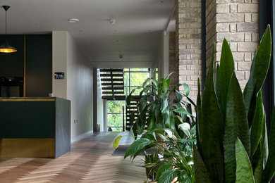 Modelo de recibidores y pasillos actuales grandes con paredes grises, suelo de madera clara, suelo marrón y iluminación