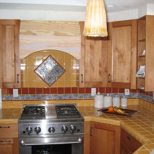 Exemple d'une petite arrière-cuisine sud-ouest américain en L avec un évier posé, un placard avec porte à panneau encastré, des portes de placard en bois clair, un plan de travail en carrelage, une crédence jaune et un électroménager en acier inoxydable.