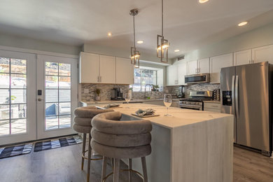 Example of a minimalist eat-in kitchen design in Los Angeles with stainless steel appliances and an island