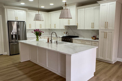 Mid-sized trendy l-shaped laminate floor and brown floor eat-in kitchen photo in Phoenix with an undermount sink, shaker cabinets, white cabinets, quartz countertops, white backsplash, quartz backsplash, an island and white countertops