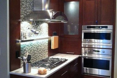 Large trendy porcelain tile kitchen photo in Other with an undermount sink, recessed-panel cabinets, dark wood cabinets, granite countertops, brown backsplash, glass sheet backsplash, stainless steel appliances and an island