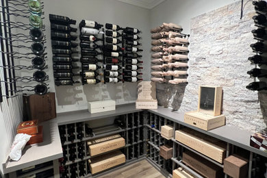Medium sized modern wine cellar in Cincinnati with light hardwood flooring, display racks and brown floors.