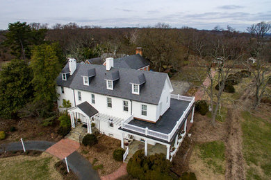 Example of a large classic white three-story stucco exterior home design in DC Metro with a shingle roof