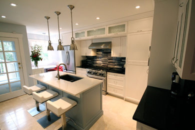 This is an example of a traditional l-shaped eat-in kitchen in Vancouver with an undermount sink, white cabinets, recessed-panel cabinets, multi-coloured splashback, glass tile splashback and stainless steel appliances.