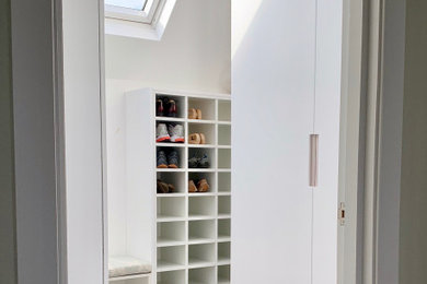Inspiration for a small contemporary gender neutral walk-in wardrobe in Essex with flat-panel cabinets, white cabinets, carpet and beige floors.