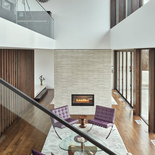 Imagen de salón para visitas tipo loft, moderno, de tamaño medio, sin televisor, con paredes blancas, marco de chimenea de baldosas y/o azulejos, suelo de madera en tonos medios, suelo marrón y chimenea de doble cara