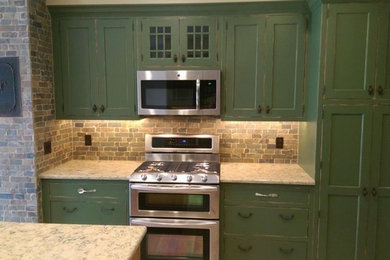 Kitchen - mid-sized cottage u-shaped light wood floor kitchen idea in Other with shaker cabinets, green cabinets, granite countertops, multicolored backsplash, stone tile backsplash, an island, a farmhouse sink and stainless steel appliances