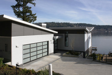 На фото: двухэтажный, серый частный загородный дом среднего размера в современном стиле с комбинированной облицовкой и односкатной крышей