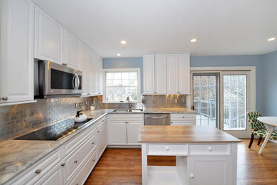 Mid-sized trendy u-shaped light wood floor and beige floor eat-in kitchen photo in St Louis with white cabinets, stainless steel appliances, a double-bowl sink, raised-panel cabinets, metallic backsplash, subway tile backsplash, gray countertops, marble countertops and an island