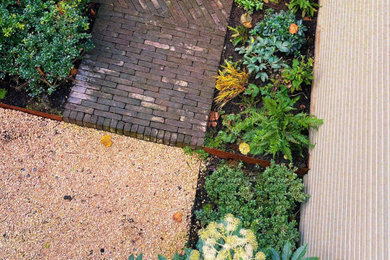 This is an example of a small contemporary back formal and private partial sun garden for autumn in London with brick paving and a wood fence.