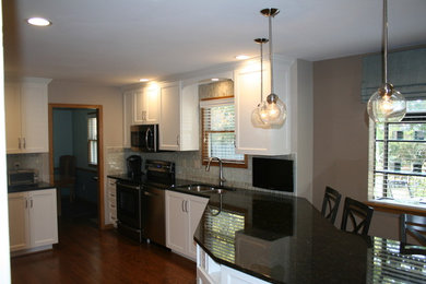 Eat-in kitchen - mid-sized traditional l-shaped dark wood floor and brown floor eat-in kitchen idea in Columbus with a double-bowl sink, shaker cabinets, white cabinets, quartz countertops, gray backsplash, subway tile backsplash, stainless steel appliances, a peninsula and black countertops