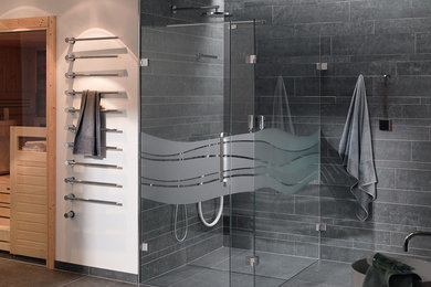 Photo of a contemporary bathroom in Essen with a curbless shower, gray tile, stone slab, grey walls, ceramic floors, grey floor and a hinged shower door.
