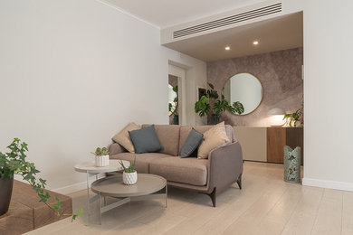 This is an example of a mid-sized contemporary open concept living room in Rome with beige walls, light hardwood floors and a wall-mounted tv.