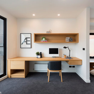 Diseño de despacho contemporáneo con paredes blancas, moqueta, escritorio empotrado y suelo negro