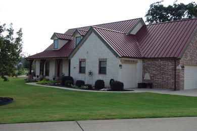 This is an example of a large country two-storey red house exterior in Dallas with mixed siding, a gable roof and a metal roof.