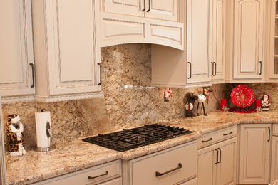 Inspiration for a mid-sized timeless l-shaped porcelain tile and beige floor enclosed kitchen remodel in Burlington with raised-panel cabinets, white cabinets, granite countertops, beige backsplash, stone slab backsplash, stainless steel appliances, an island and an undermount sink