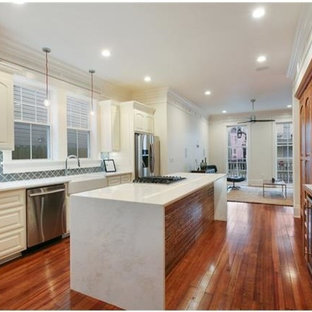 Mid-sized traditional kitchen pantry appliance - Example of a mid-sized classic galley light wood floor kitchen pantry design in New Orleans with a farmhouse sink, raised-panel cabinets, white cabinets, marble countertops, blue backsplash, stainless steel appliances and an island