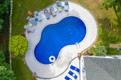 Inspiration for a large contemporary backyard tile and custom-shaped natural pool landscaping remodel in New York