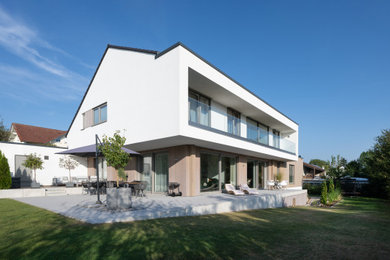 Großes Modernes Einfamilienhaus mit Mix-Fassade, weißer Fassadenfarbe, Satteldach, Ziegeldach, grauem Dach und Verschalung in Frankfurt am Main