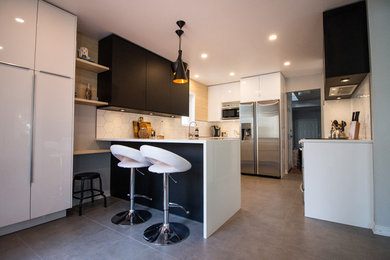 Example of a mid-sized danish u-shaped porcelain tile and gray floor eat-in kitchen design in Ottawa with an undermount sink, flat-panel cabinets, white cabinets, quartz countertops, white backsplash, ceramic backsplash, stainless steel appliances and a peninsula