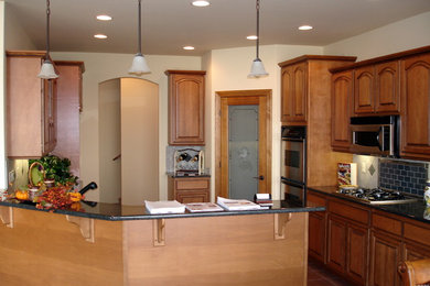 Inspiration for a mid-sized u-shaped ceramic tile enclosed kitchen remodel in Seattle with an undermount sink, raised-panel cabinets, medium tone wood cabinets, granite countertops, gray backsplash, subway tile backsplash, stainless steel appliances and a peninsula