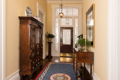 オースティンにある小さなトラディショナルスタイルのおしゃれな玄関 (黄色い壁、濃色無垢フローリング、茶色いドア、茶色い床) の写真