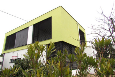 Mittelgroßes, Zweistöckiges Modernes Einfamilienhaus mit Betonfassade, grüner Fassadenfarbe, Flachdach, Ziegeldach und grauem Dach in Sonstige