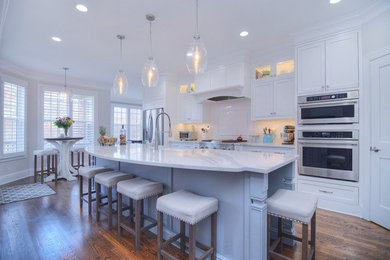 Kitchen - traditional dark wood floor and brown floor kitchen idea in Charleston with a farmhouse sink, blue cabinets, quartz countertops, white backsplash, ceramic backsplash, stainless steel appliances, an island and white countertops