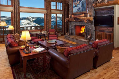 Photo of a large country formal open concept living room in Denver with beige walls, medium hardwood floors, a standard fireplace, a stone fireplace surround and a wall-mounted tv.
