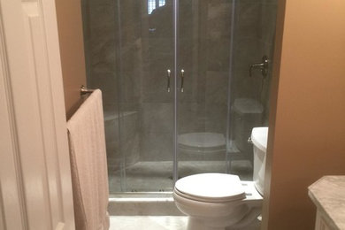Example of a mid-sized cottage chic master beige tile and porcelain tile porcelain tile alcove shower design in Baltimore with an undermount sink, furniture-like cabinets, white cabinets, marble countertops, a two-piece toilet and brown walls