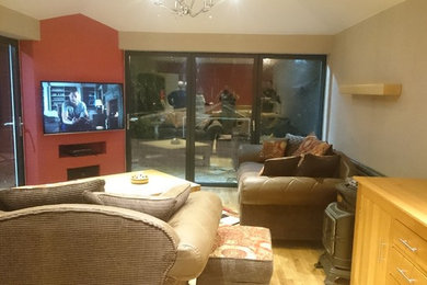 This is an example of a medium sized contemporary open plan games room in Manchester with light hardwood flooring and a wall mounted tv.