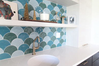 Example of a mid-sized mid-century modern single-wall medium tone wood floor and brown floor wet bar design in Seattle with an undermount sink, flat-panel cabinets, dark wood cabinets, quartz countertops, multicolored backsplash and white countertops