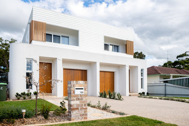 This is an example of a large modern two-storey brick white duplex exterior in Wollongong with a flat roof, a metal roof and a white roof.