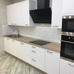 Aménagement d'une arrière-cuisine linéaire scandinave de taille moyenne avec un évier posé, un placard à porte plane, des portes de placard blanches, un plan de travail en stratifié, une crédence blanche, une crédence en carrelage métro, un électroménager noir, un sol en carrelage de porcelaine, aucun îlot, un sol gris et un plan de travail beige.