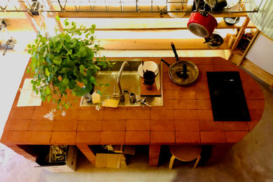 Aménagement d'une cuisine parallèle contemporaine avec un évier posé, un électroménager en acier inoxydable, sol en béton ciré, îlot, un sol gris, un plan de travail rouge et poutres apparentes.
