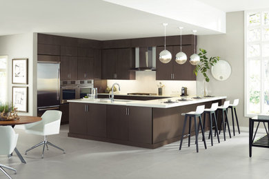 Large trendy gray floor eat-in kitchen photo in New York with flat-panel cabinets, dark wood cabinets, white backsplash, stainless steel appliances, a peninsula and white countertops