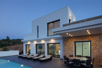 Diseño de fachada de casa blanca moderna de tamaño medio de dos plantas con revestimiento de piedra y tejado plano