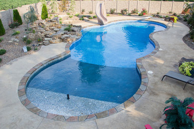 Inspiration for a large tropical backyard stamped concrete and custom-shaped pool fountain remodel in Chicago